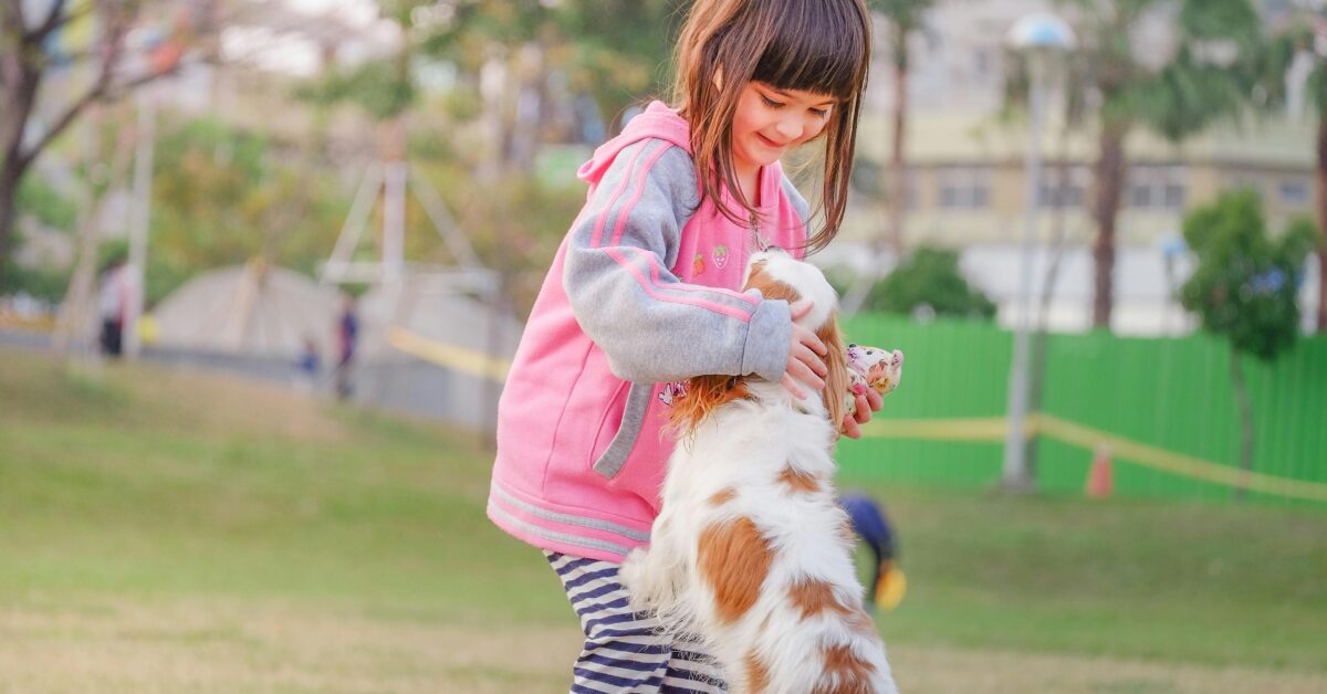 A little girl playing with a dog in the park