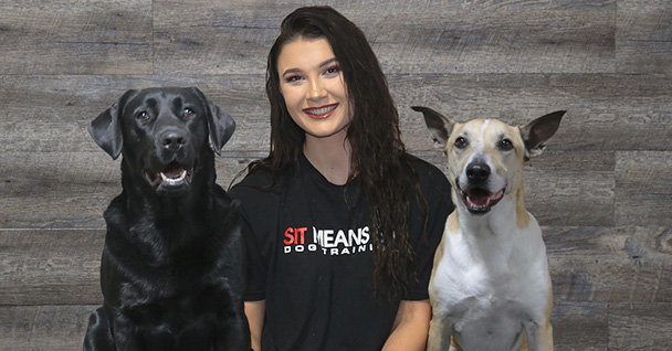 a woman sitting between two dogs posing for a photo