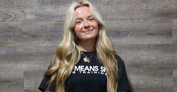a woman smiling for a photo Infront of a wooden wall