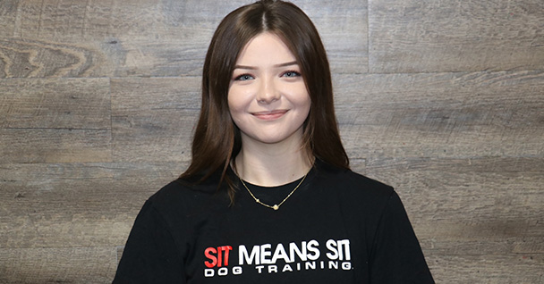 a woman smiling for a photo Infront of a wooden wall