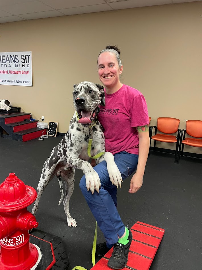 Dog and trainer posing for a photo with the dog resting on the trainers leg.