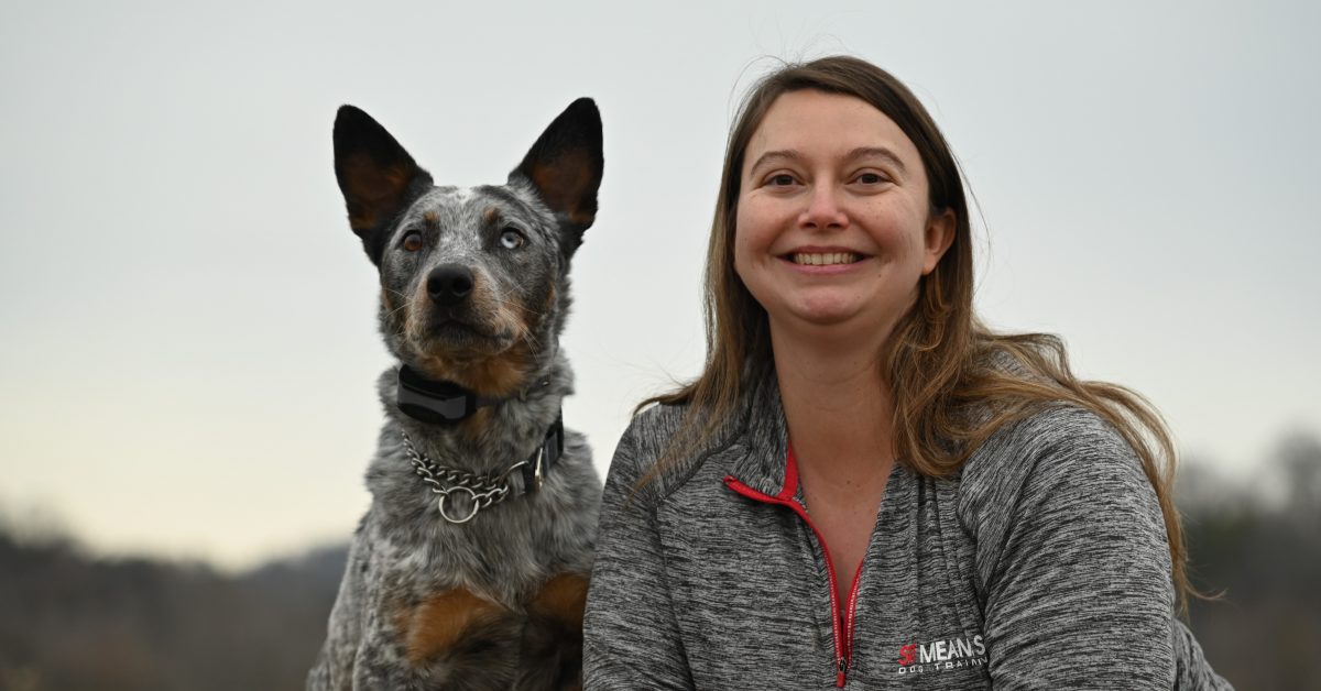a woman smiling wide posing with a dog for a picture