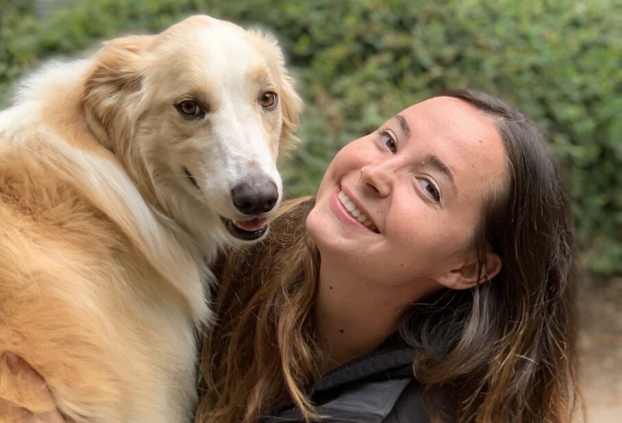 woman holding her labrador with plants in background