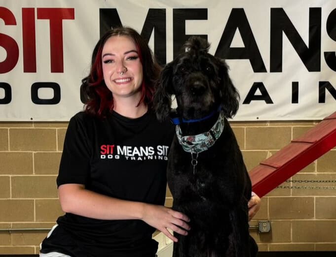 A woman and black dog smiling for a photo